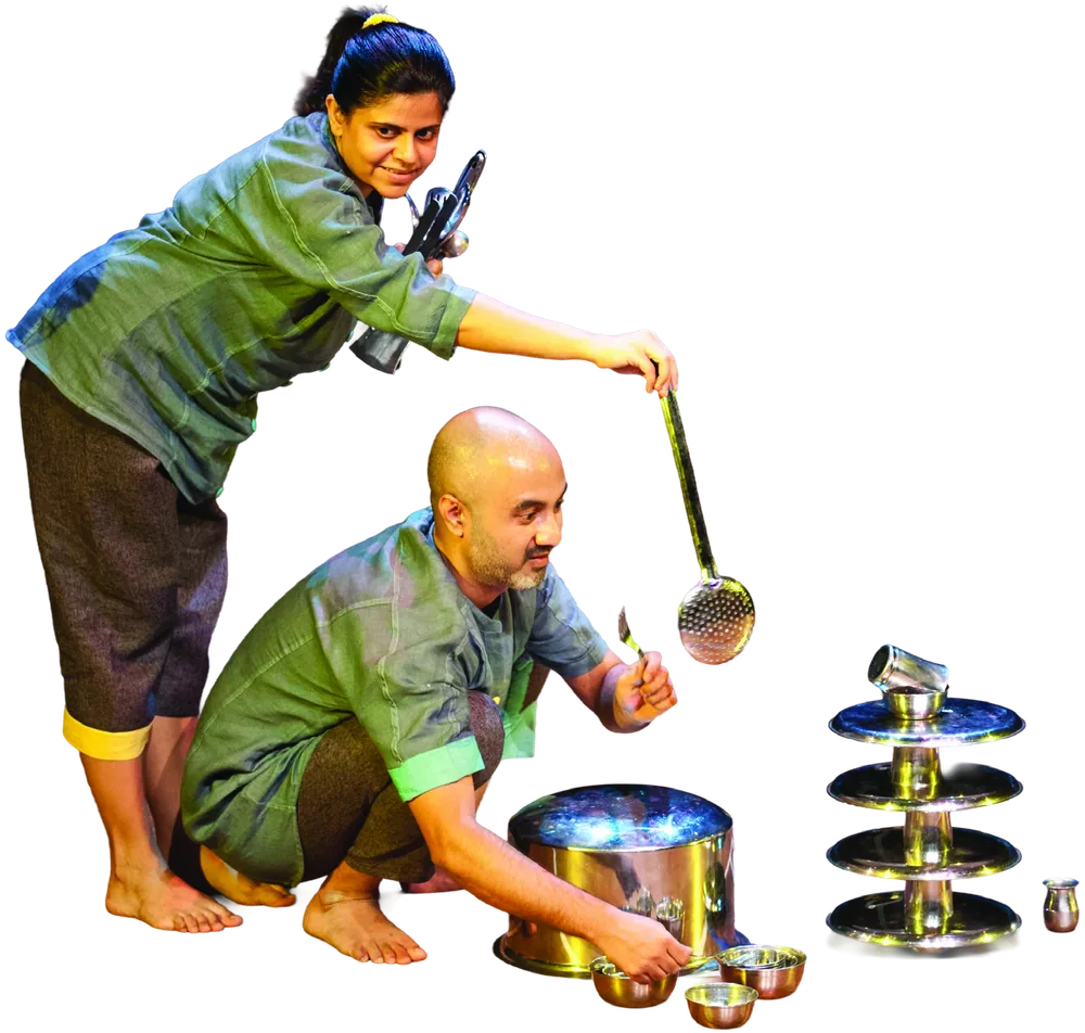 Two performers with a ladle, a steel pot and a tower of stacked steel plates.