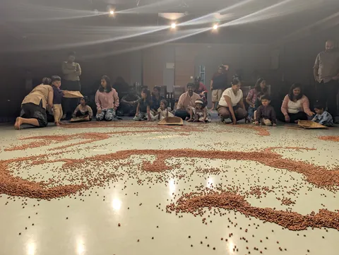 Wide view of the finished spiral of gram, children and adults seated around its edge.