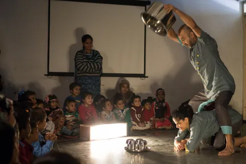 A child watches from the front edge of the playing space.